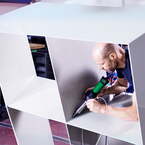 Tradesman welds thermoplastic membrane with Leister Triac AT heat gun for waterproof roofing seams